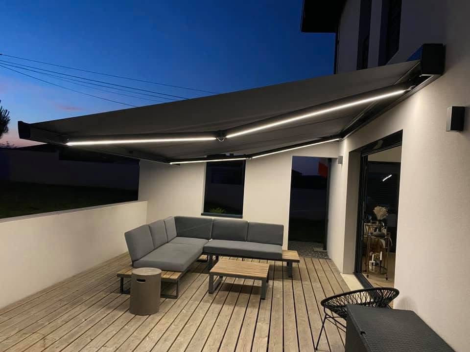 Store banne anthracite avec éclairage LED installé sur une terrasse en bois