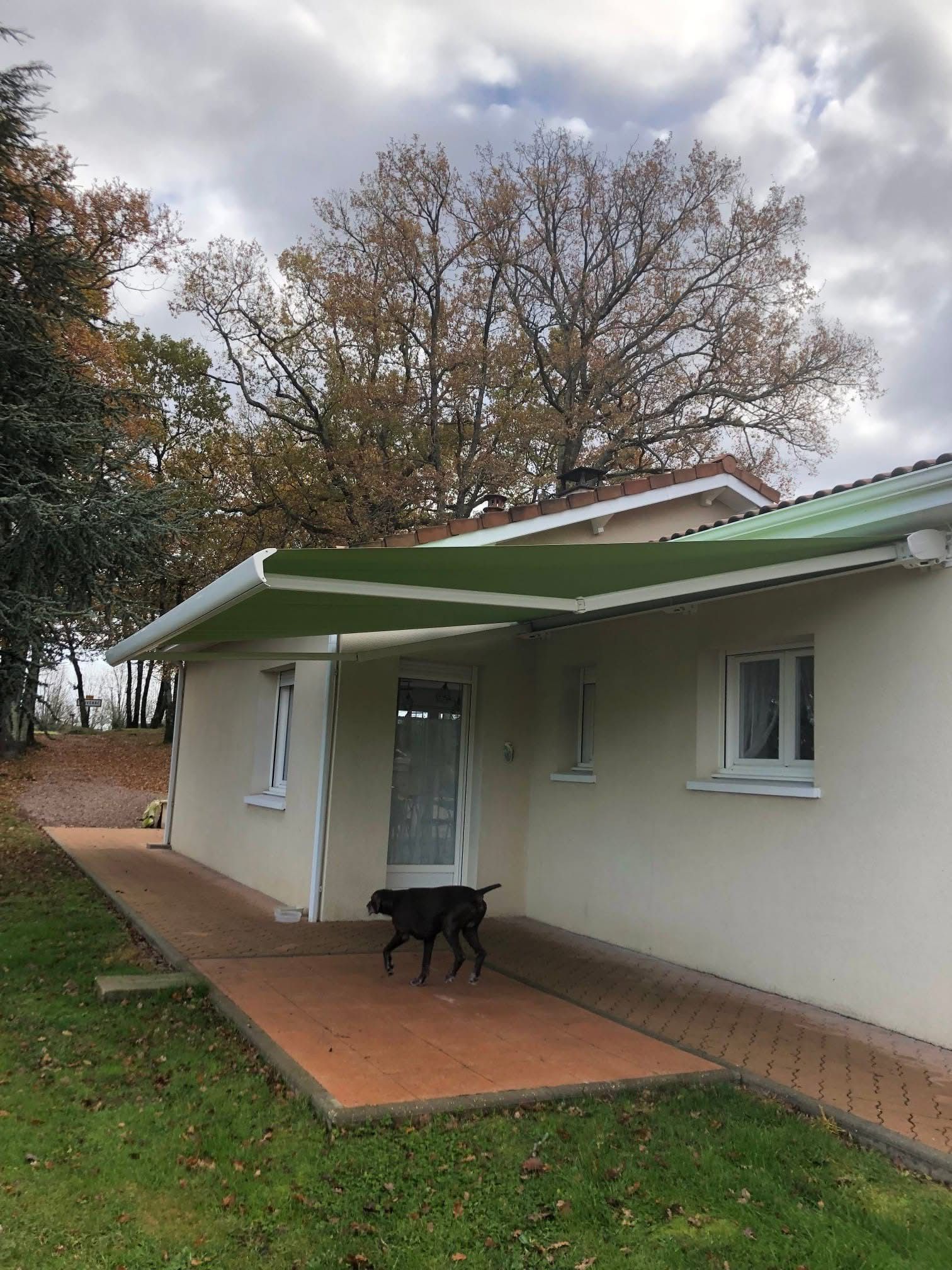 Store banne vert déployé sur la terrasse d'une maison