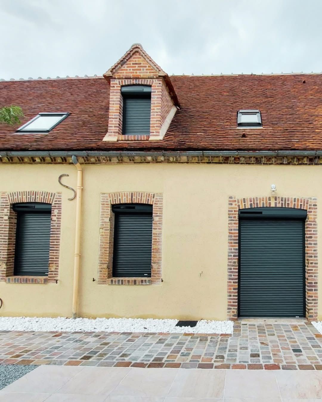 Volets roulants anthracite installés sur une maison en brique